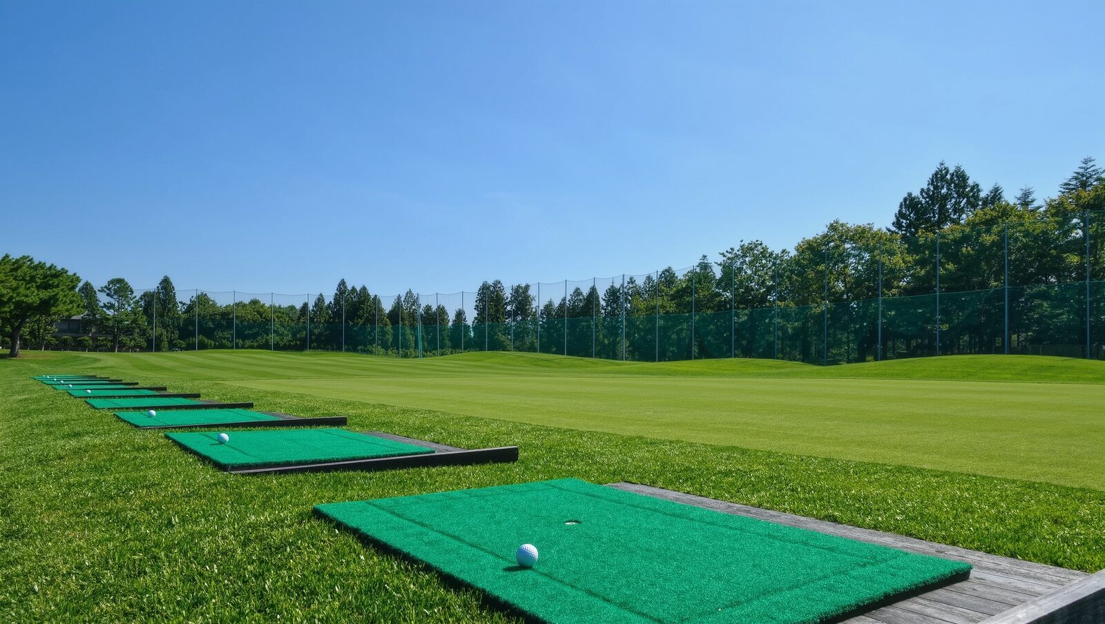 Empty driving range with green hitting mats and white golf balls